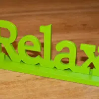 A wooden sign that says relax on top of a wooden table, providing a calming ambiance to your bathroom space.