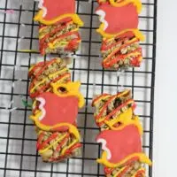 Colorful frosted cookies designed to look like descendants on a cooling rack.
