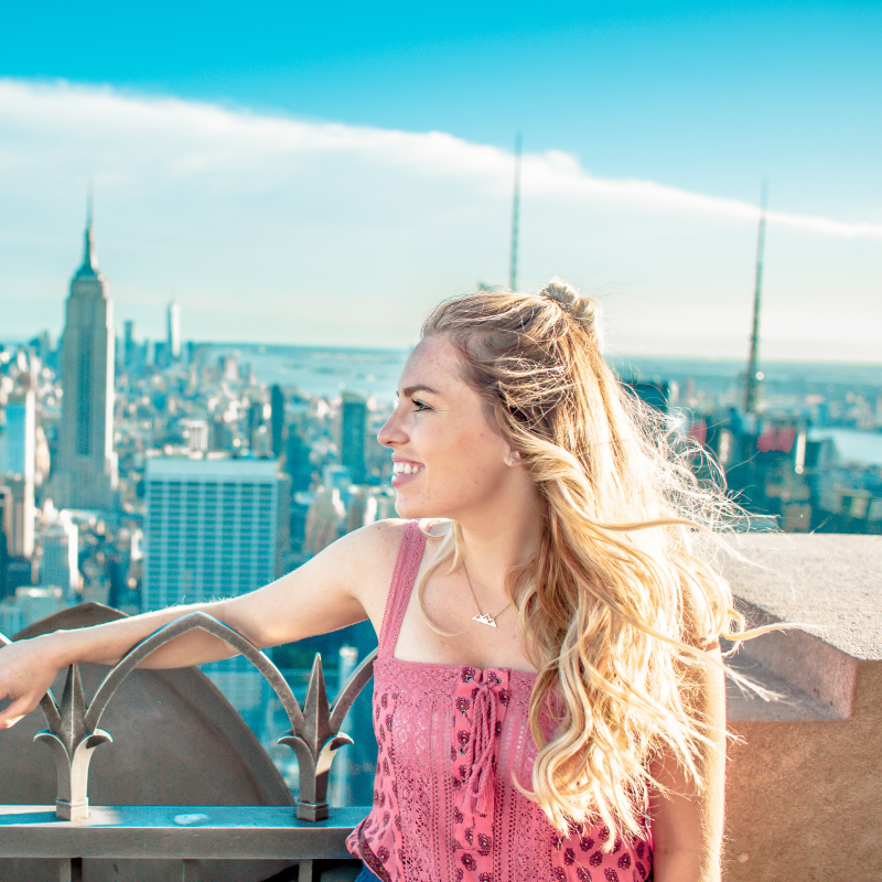 woman on top of tower and overlooking Empire State Building