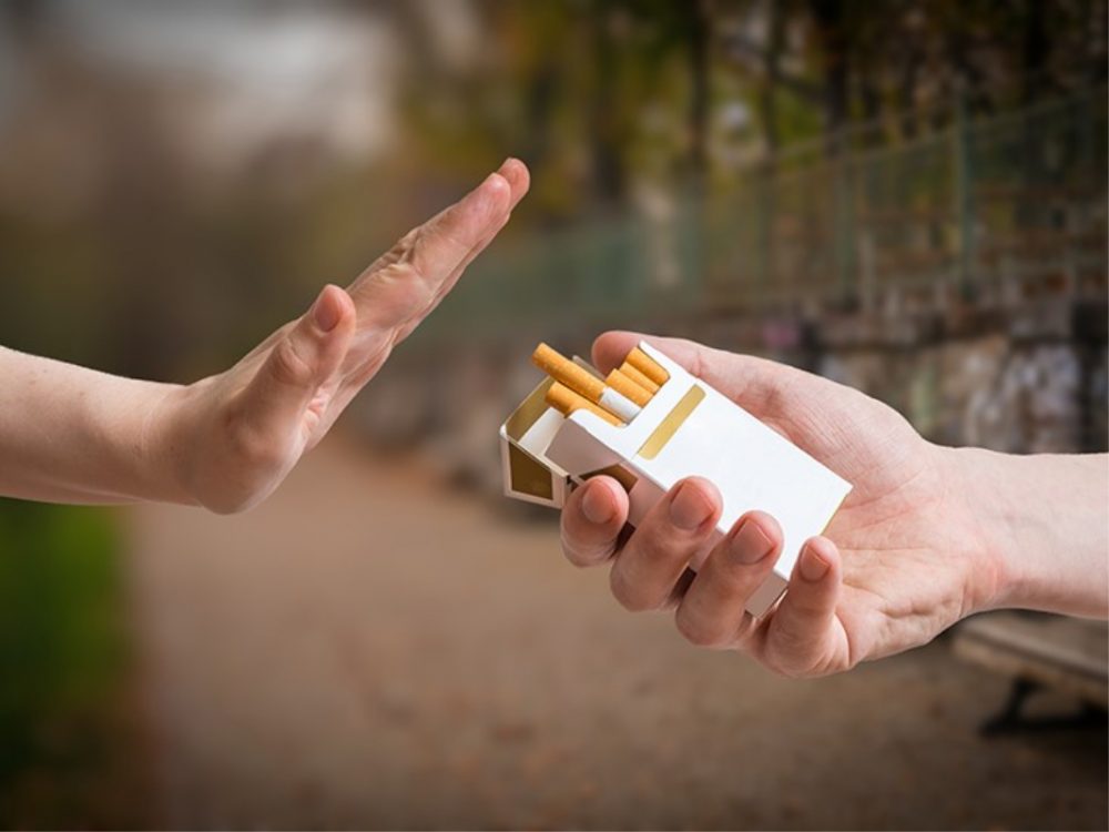 hand waving away cigarette pack 