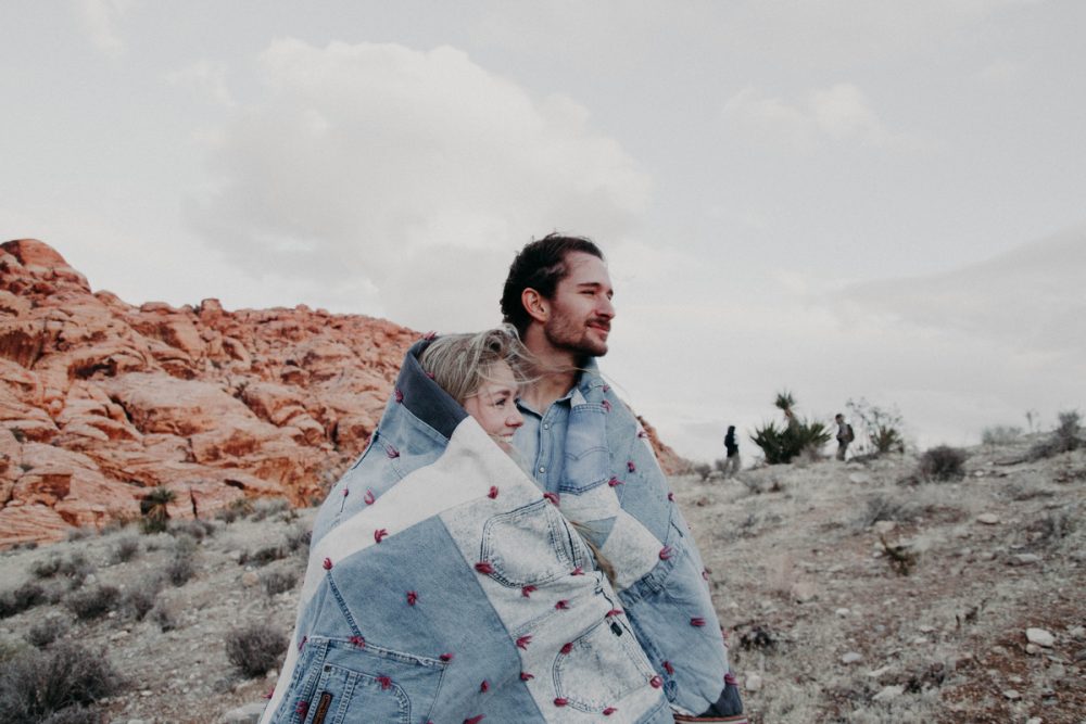 man and woman covered in blue blanket