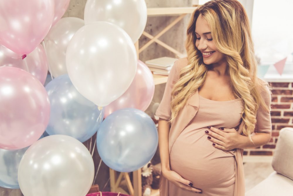 woman holding stomach surrounded by ballons