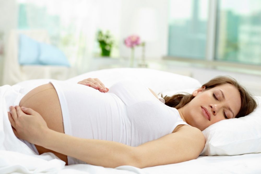 lady sleeping with hand on pregnant stomach