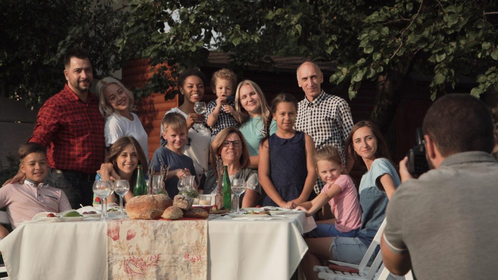 Cheerful family standing at table in garden and posing for photo.