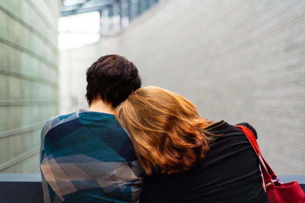 man and woman standing near gray metal fence