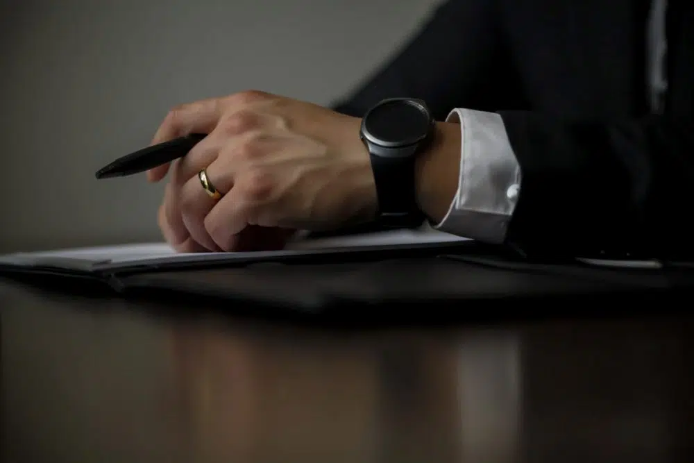 hands on desk, holding pen