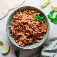 Instant Pot Mexican Carnitas in a blue bowl with tortillas