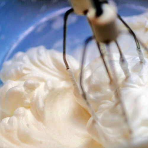 Mixing white egg cream in bowl with electric mixer, baking cake