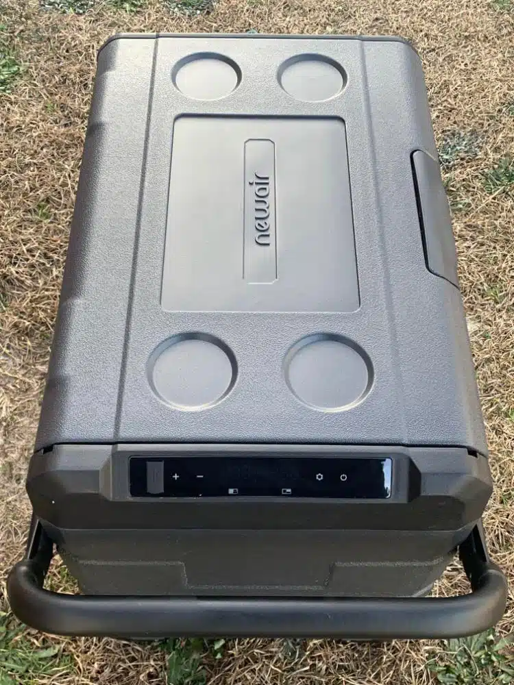 A portable, 48 Qt. black cooler sitting on a grassy area.