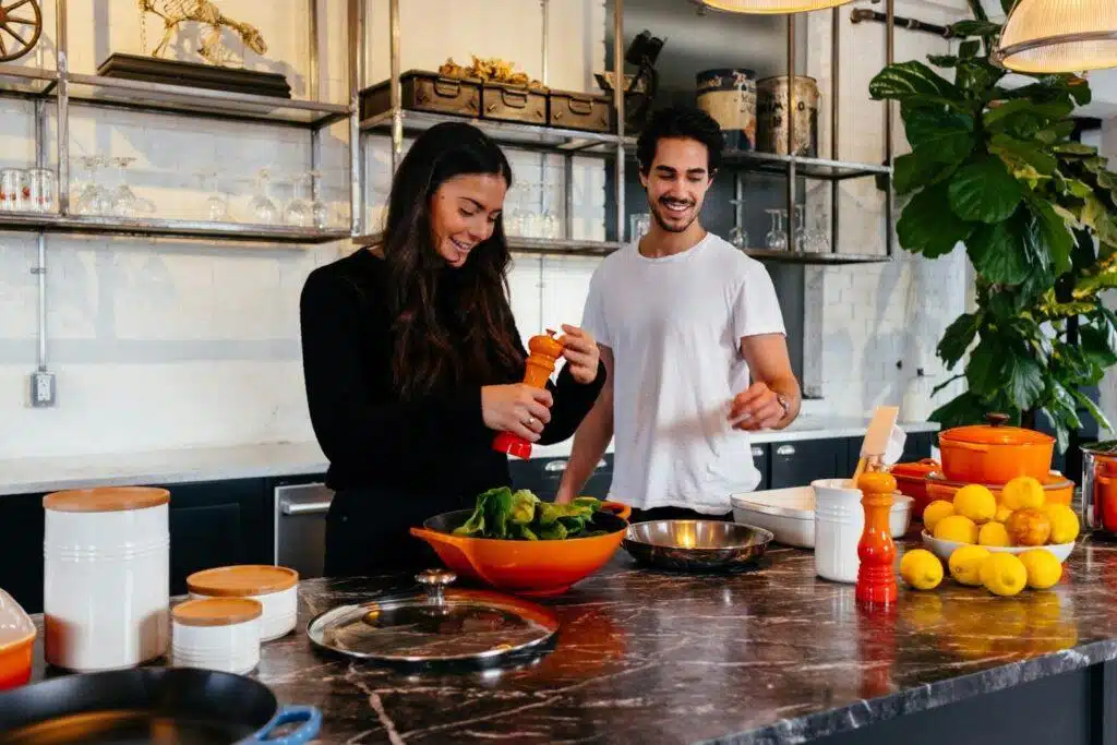 A man and woman are preparing healthier food in a kitchen.