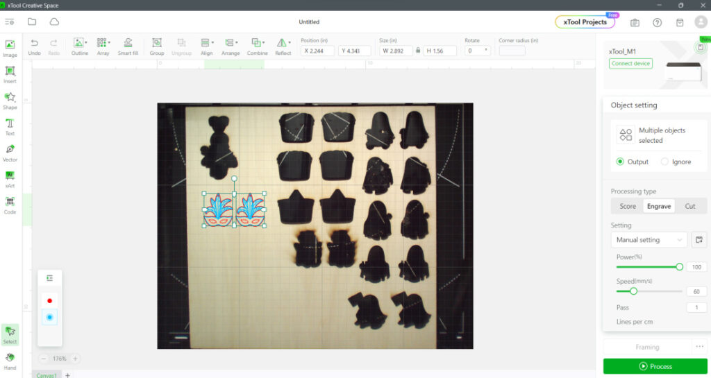 Screenshot of xTool Creative Space displaying a grid with various black shapes and a vibrant design resembling Mardi Gras mask earrings. Toolbars and settings are visible at the top and sides of the workspace.