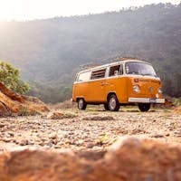 Classic VW van parked on rocky terrain with mountains in Alegría, El Salvador.
