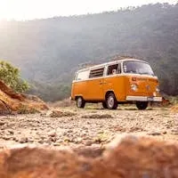 Classic VW van parked on rocky terrain with mountains in Alegría, El Salvador.