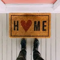A creative doormat with heart motif symbolizing home at a front porch entrance.