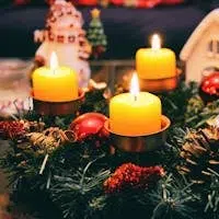 Cozy Christmas display featuring candles, ornaments, and festive wreath in warm candlelight.