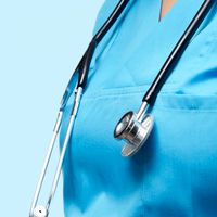 Close-up of a healthcare worker in scrubs with a stethoscope against a blue backdrop.