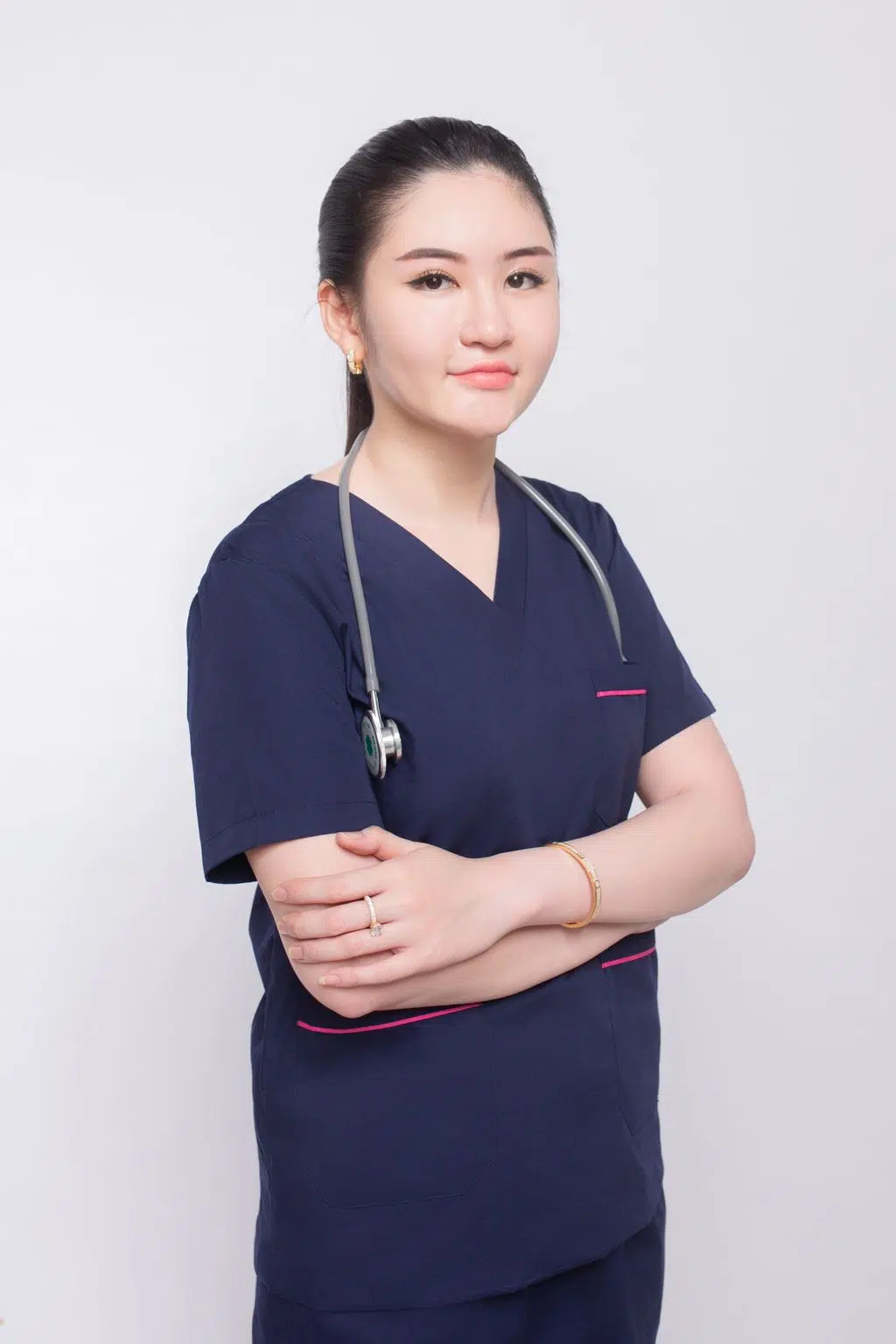 Portrait of a young female healthcare professional with crossed arms in a studio setting.