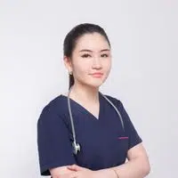 Portrait of a young female healthcare professional with crossed arms in a studio setting.