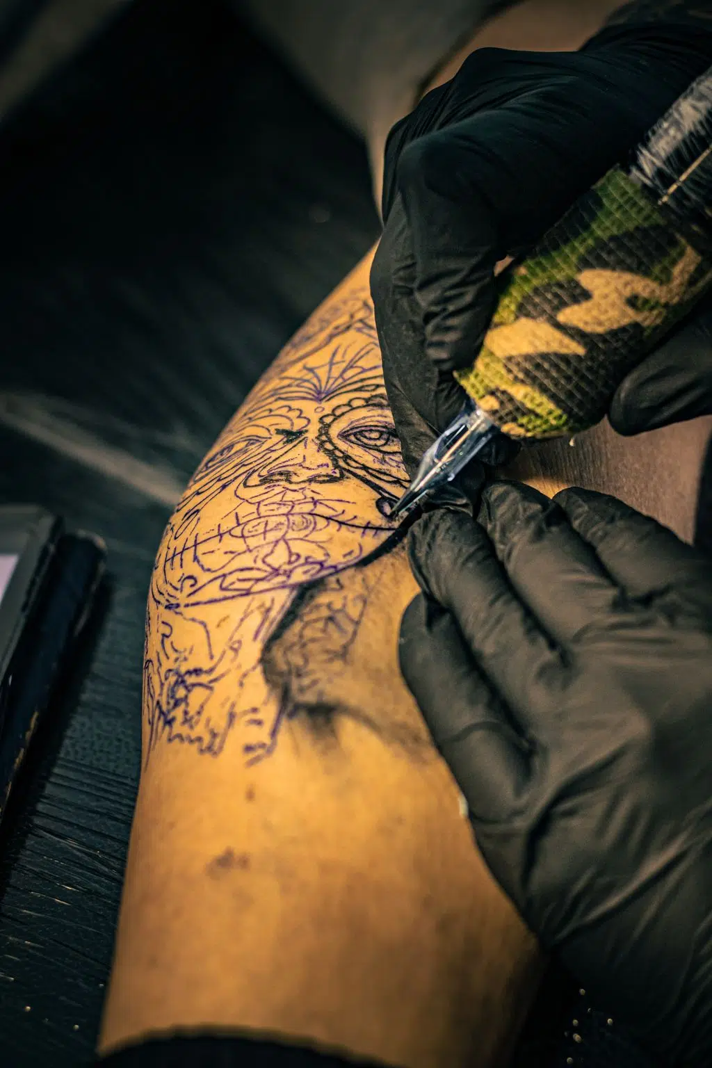 Artistic tattoo design process on arm in a tattoo studio, showcasing intricate craftsmanship and tattoo culture.
