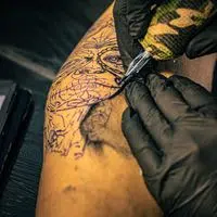 Artistic tattoo design process on arm in a tattoo studio, showcasing intricate craftsmanship and tattoo culture.