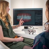A dentist explains a 3D dental model to a patient during a consultation in Edinburgh.