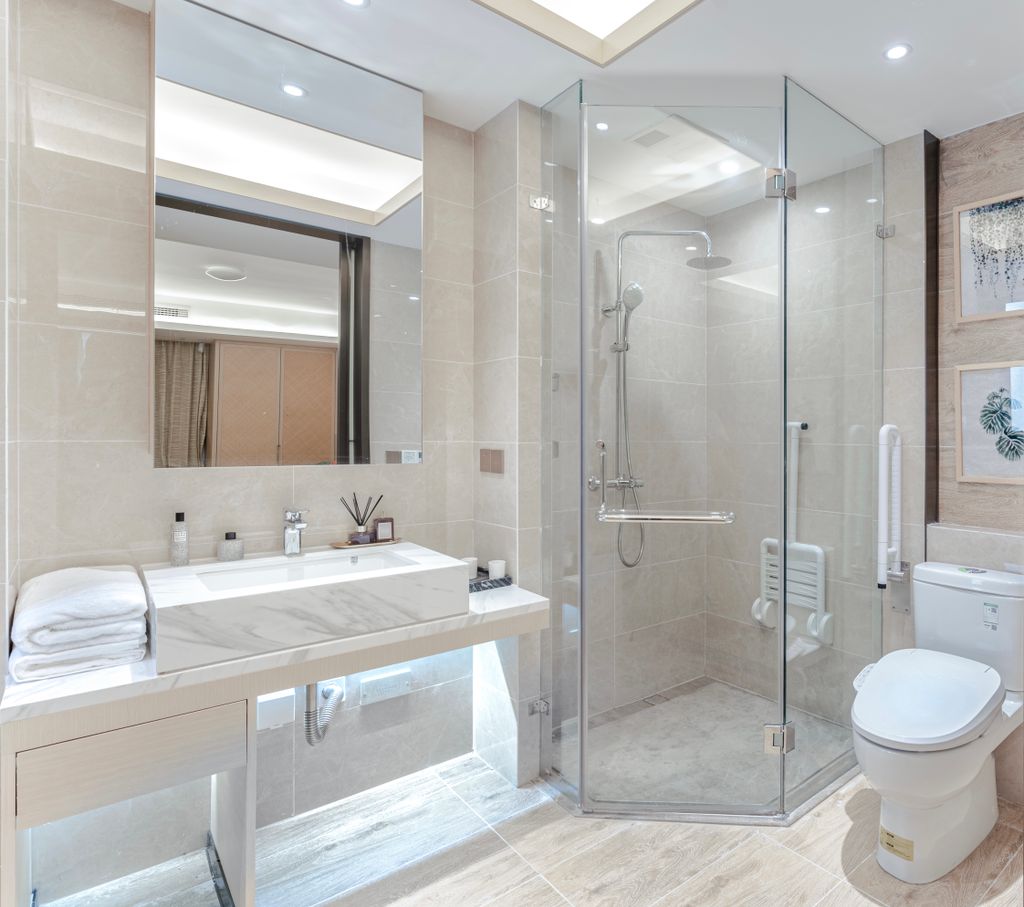 A stylish bathroom featuring a glass shower, marble sink, and elegant decor.