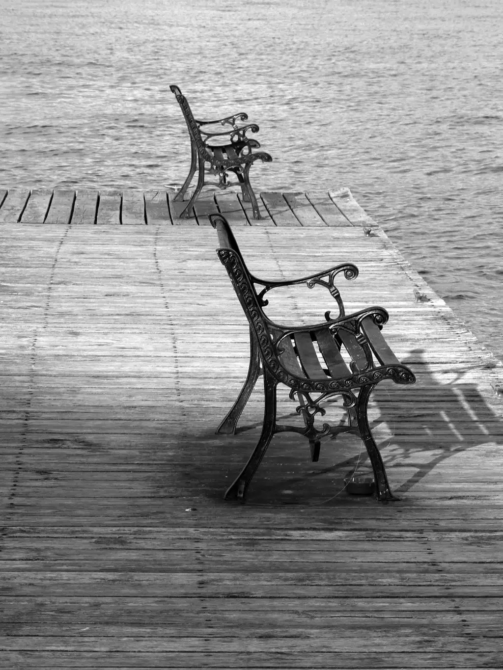 Black and white photo of empty benches on a lakeside pier in Guntersville, Alabama.