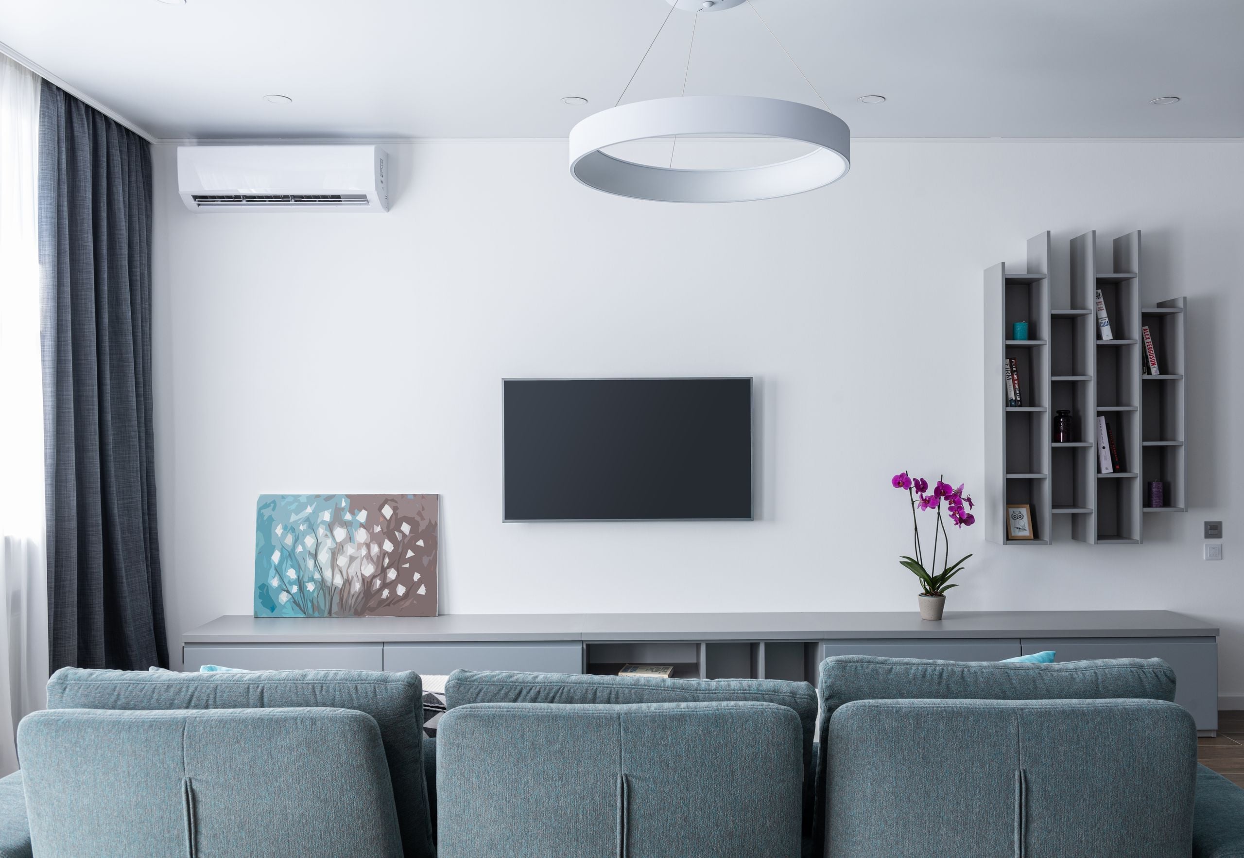 Contemporary living room with soft gray sofa and shelves decorating wall in daytime