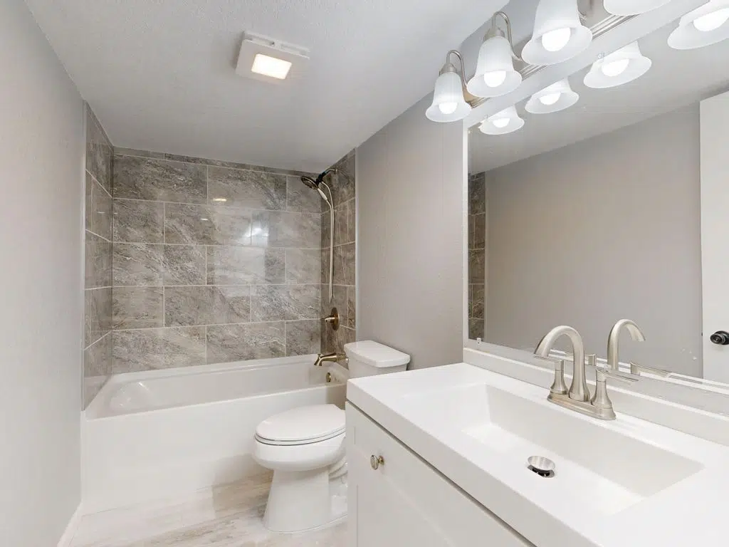 Elegant modern bathroom featuring marble tiles and sleek white vanity.