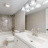 Elegant modern bathroom featuring marble tiles and sleek white vanity.