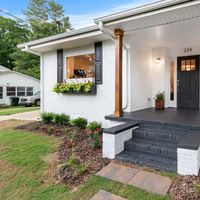 Front view of a charming white brick suburban house with black accents.