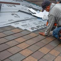 Skilled roofer installing asphalt shingles, ensuring quality home renovation.
