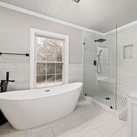 Sleek bathroom featuring a freestanding tub, glass shower, and marble accents.