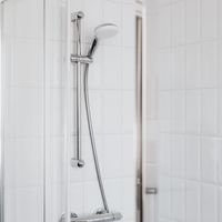 Stylish shower setup with chrome fixtures and clean white tiles.
