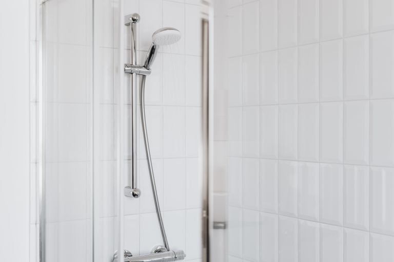 Stylish shower setup with chrome fixtures and clean white tiles.