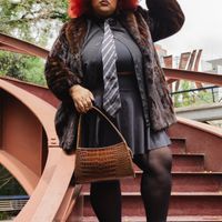 Stylish woman with pink hair, fur coat, and handbag on outdoor staircase in São Paulo.