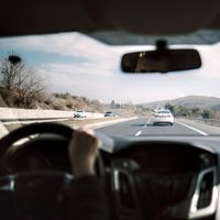 View from a car driving down a scenic highway with hills in the background, depicting a casual road trip.